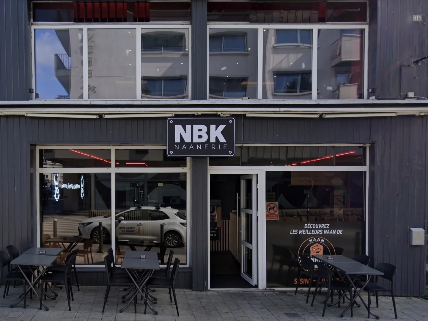 La devanture du NBK Saint-Brieuc : l’enseigne NBK Naanerie sur une façade en bardage gris, la porte ouverte, et la terrasse aux tables noires
