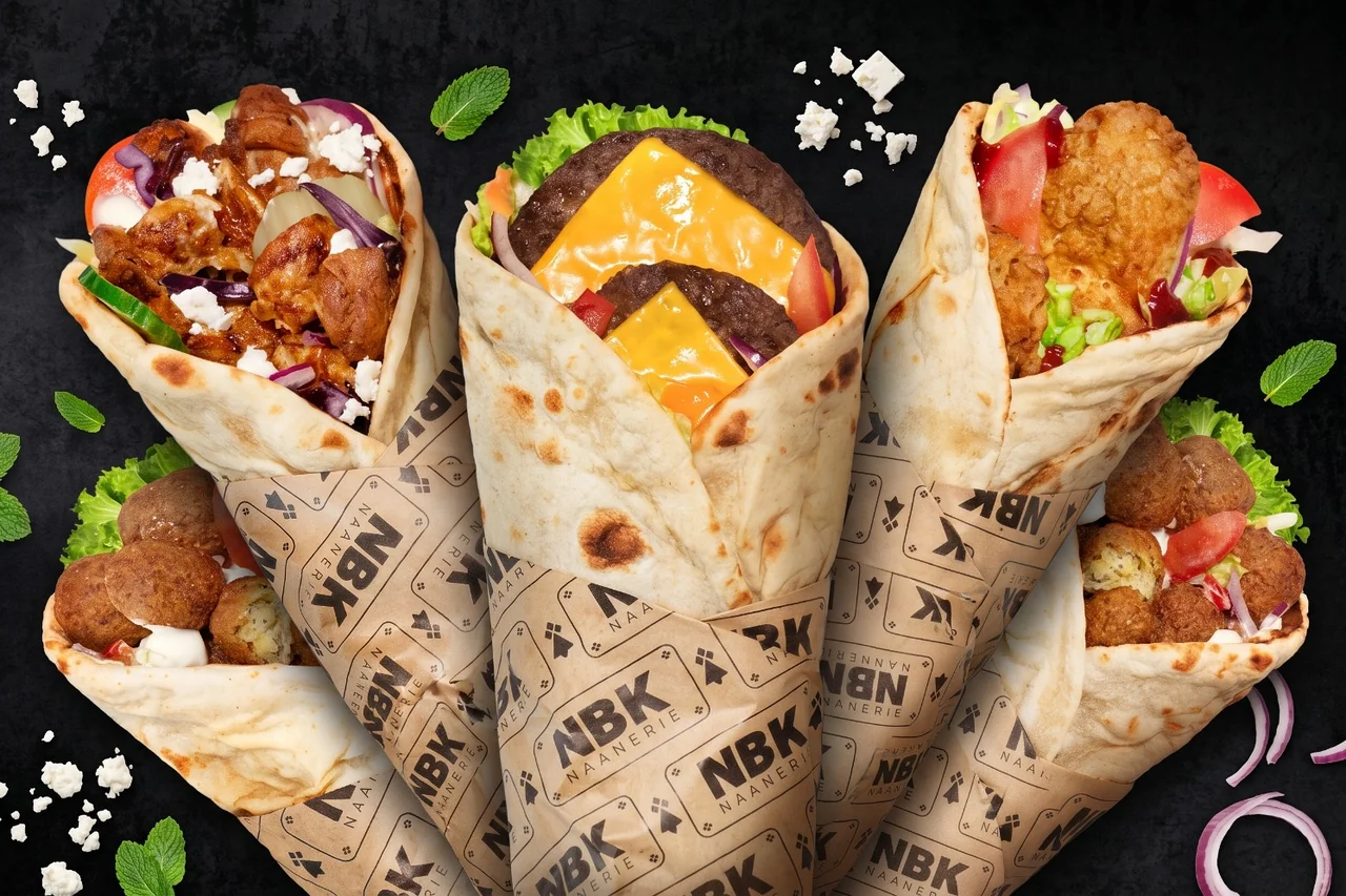Cinq cheese naans NBK dans leur papier siglé, sur fond noir : kebab et féta, steak et cheddar, poulet croustillant et falafels