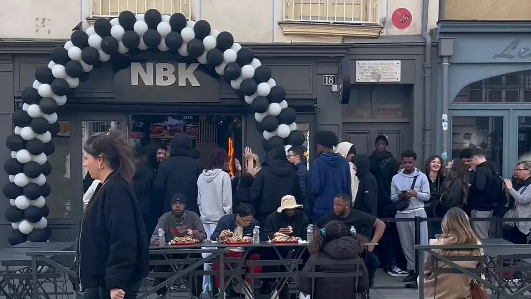 Un jour d’ouverture NBK : une arche de ballons noirs et blancs devant la devanture, la terrasse pleine et une file de clients sur le trottoir