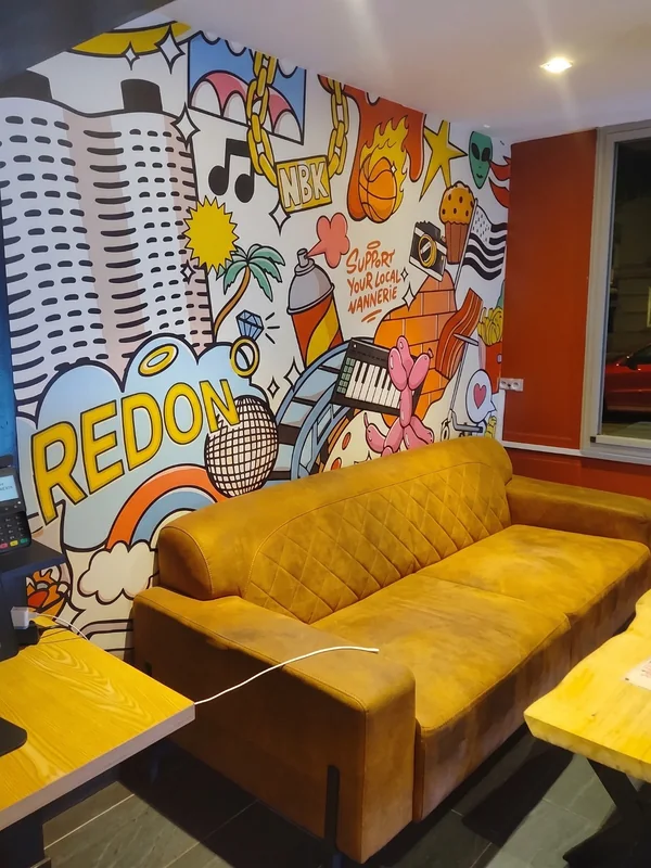 La fresque pop art du NBK Redon : le nom de la ville en grandes lettres jaunes, le drapeau breton et une chaîne en or siglée NBK, au-dessus d’un grand canapé