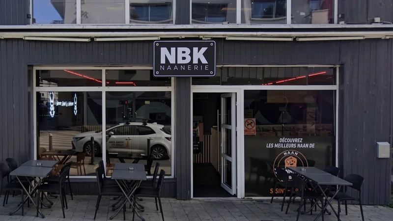 La devanture du NBK Saint-Brieuc : l’enseigne NBK Naanerie sur une façade en bardage gris, la porte ouverte, et la terrasse aux tables noires