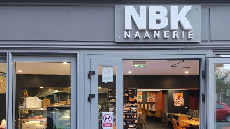 La devanture grise du NBK Redon et son enseigne NBK Naanerie : la porte ouverte sur la salle aux chaises orange, et la cuisine derrière la vitrine